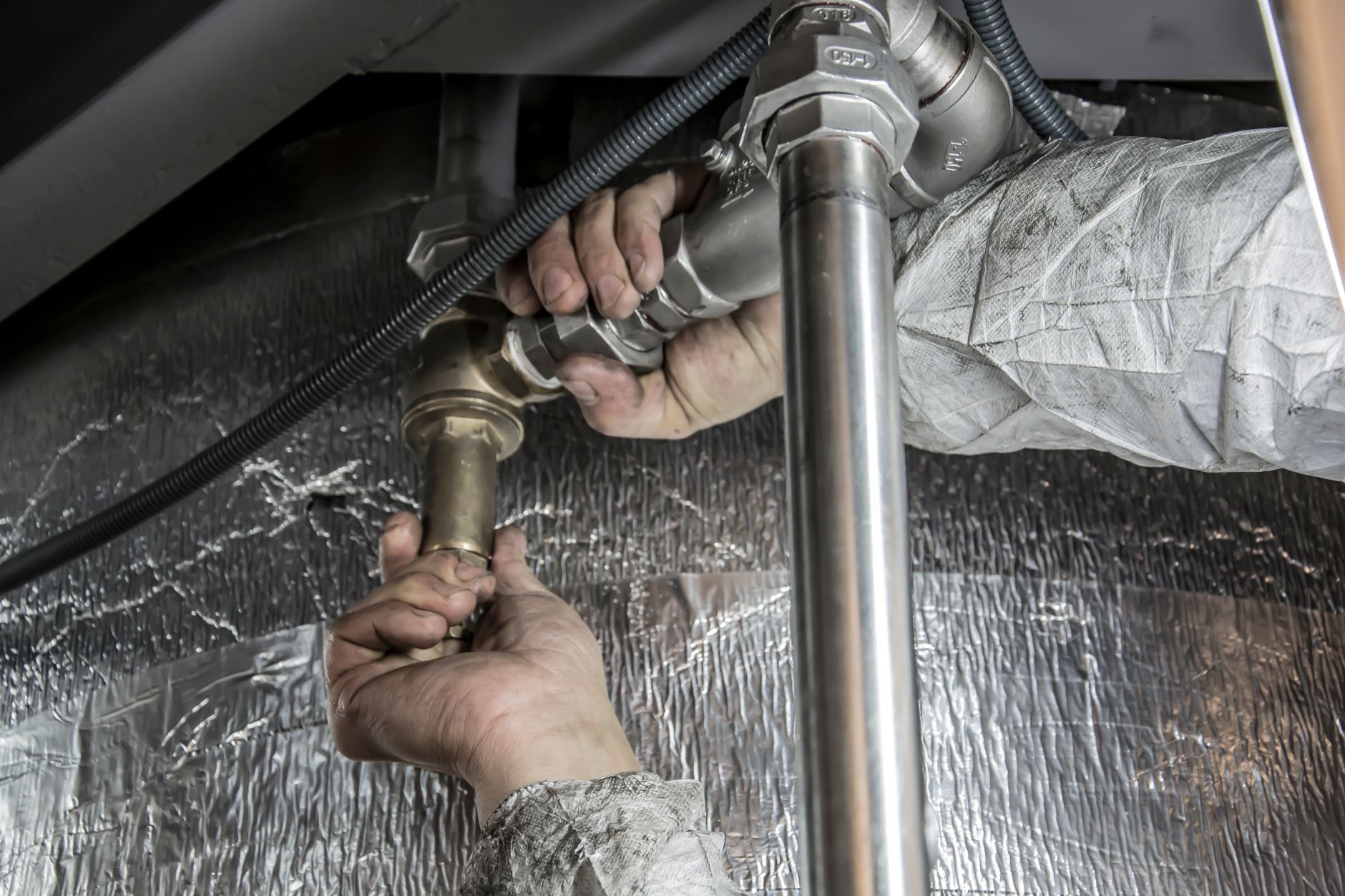 Licensed plumber repairing a burst pipe under a sink in a Dubai apartment